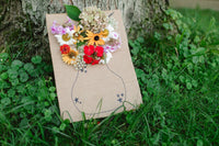 A flower vase drawn onto a piece of cardboard with real flowers sticking out of the top