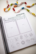 Load image into Gallery viewer, Educational worksheet on a spiral-bound book with bead decorations in the background
