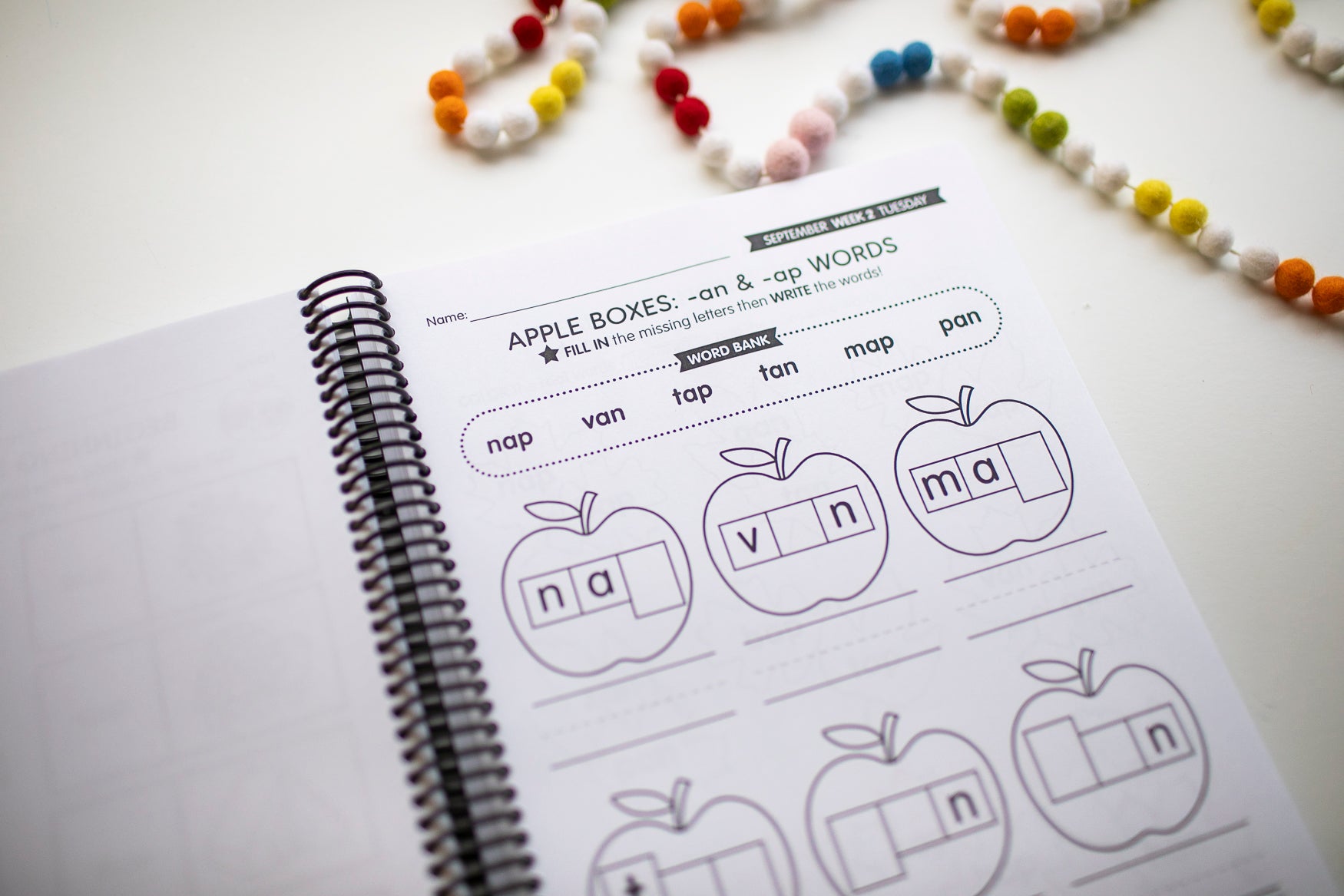 Educational worksheet with apple boxes for phonics practice on a white surface.